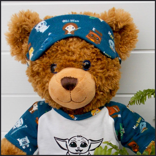 Brown teddy bear wearing pyjamas and a sleep mask