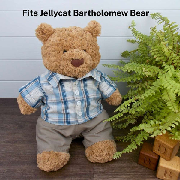 Jellycat Bartholomew teddy bear wearing a blue plaid shirt and brown trousers standing next to a potted plant and wooden blocks.