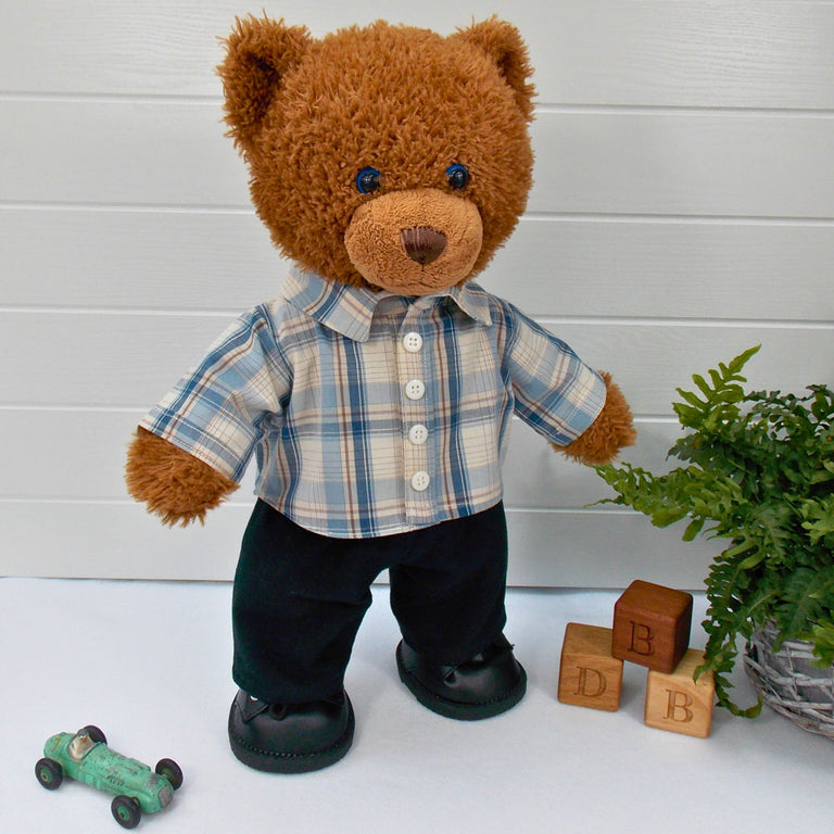 Build a bear teddy bear wearing a beige and blue checked shirt, black trousers, and black shoes. The teddy bear is standing in front of a white background. The teddy bear shirt and teddy bear trousers have been made from sewing patterns by Best Dressed Bears.