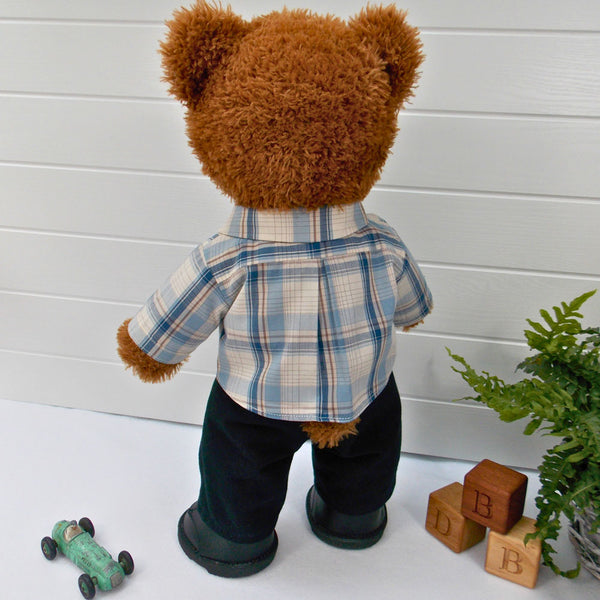 Build a bear teddy bear wearing a beige and blue checked shirt, black trousers, and black shoes. The teddy bear is standing in front of a white background. The teddy bear shirt and teddy bear trousers have been made from sewing patterns by Best Dressed Bears.