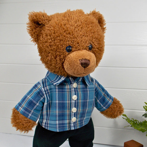 Build a bear teddy bear wearing a blue checked shirt and black trousers. The teddy bear is standing in front of a white background. The teddy bear shirt and teddy bear trousers have been made from sewing patterns by Best Dressed Bears.